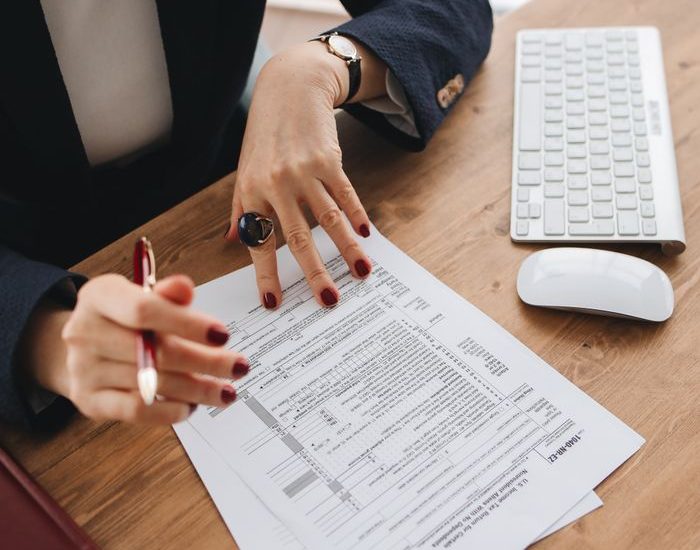 Close-up of a professional examining tax documents on a wooden desk indoors.